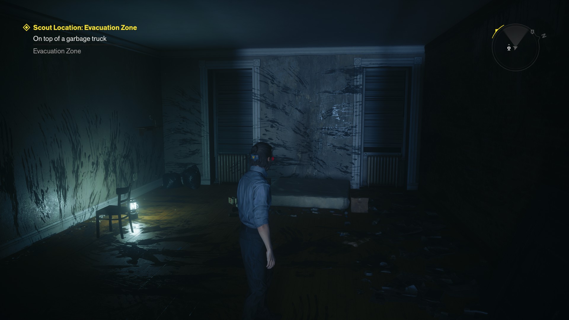 Dylan stands in an apartment building lit by a single lamp. There are smears of ink on the wall.