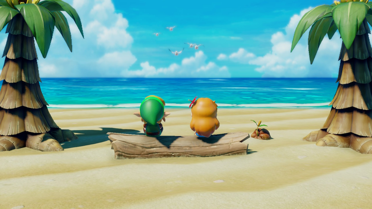 Link and Marin sit on a log in front of the ocean.